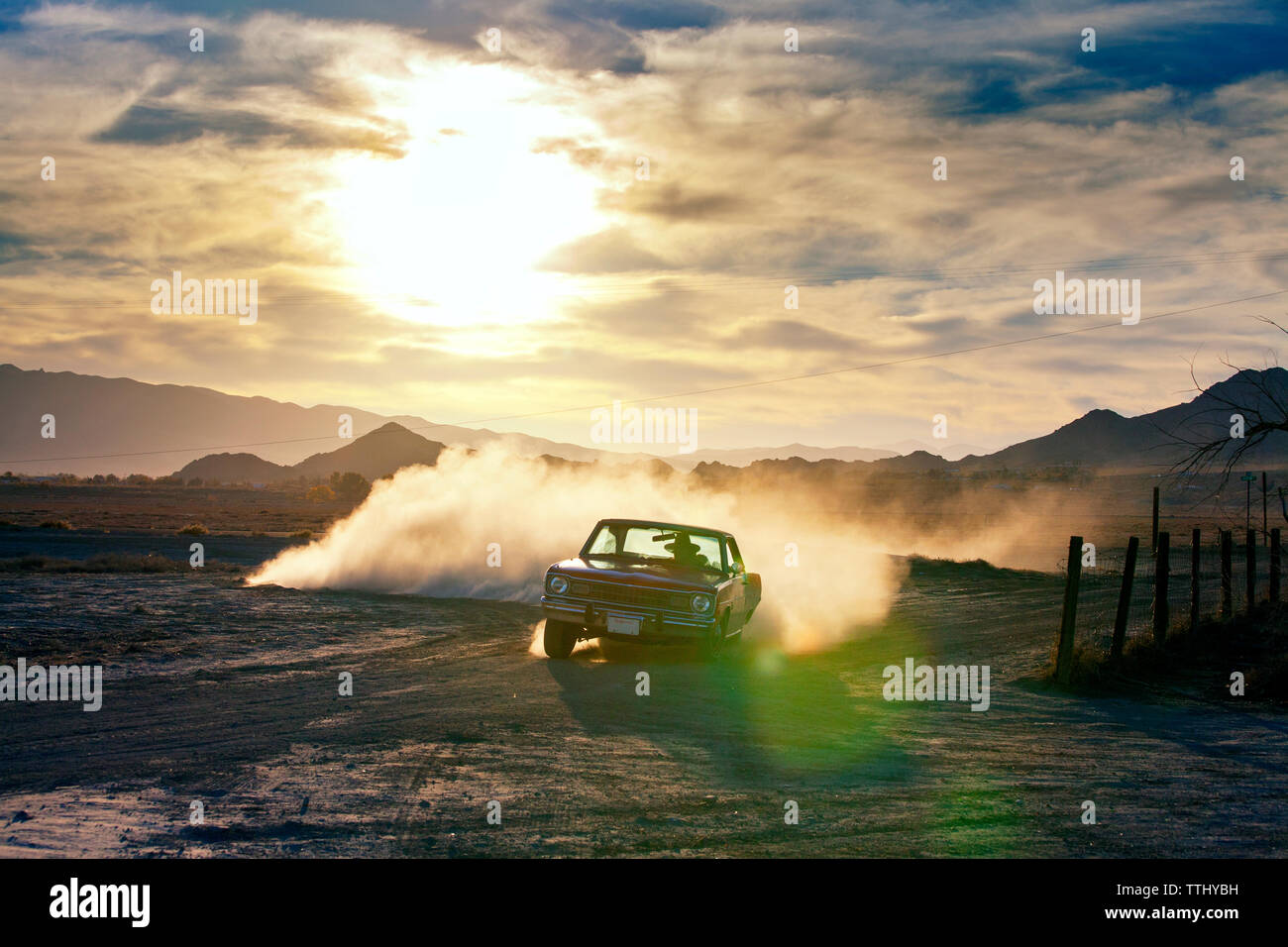 Man driving car on field during sunset Stock Photo