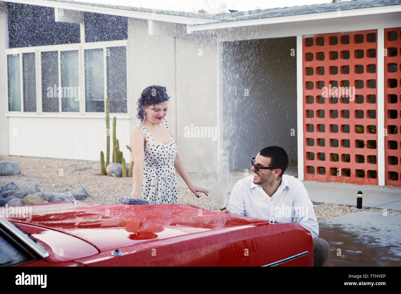 Playful couple washing car at parking lot Stock Photo