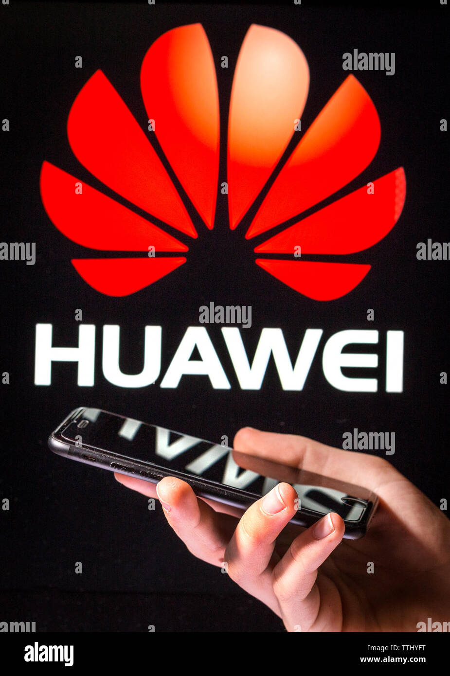 A man using a mobile phone in front of the Huawei sign (editorial use only) Stock Photo
