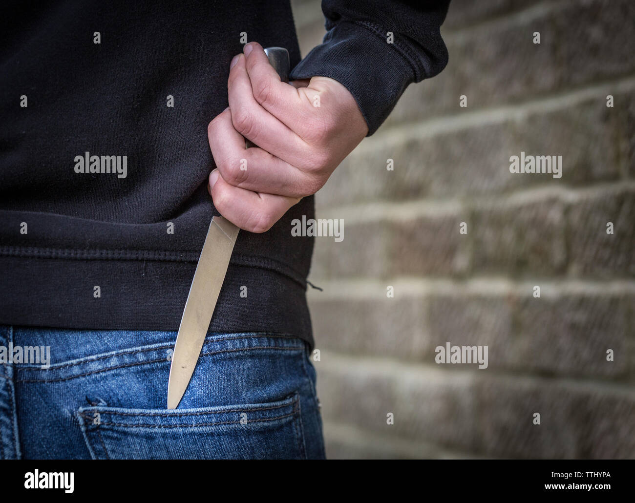 Knife Crime, Teenager in a hoody carrying a knife on the street in the UK Stock Photo