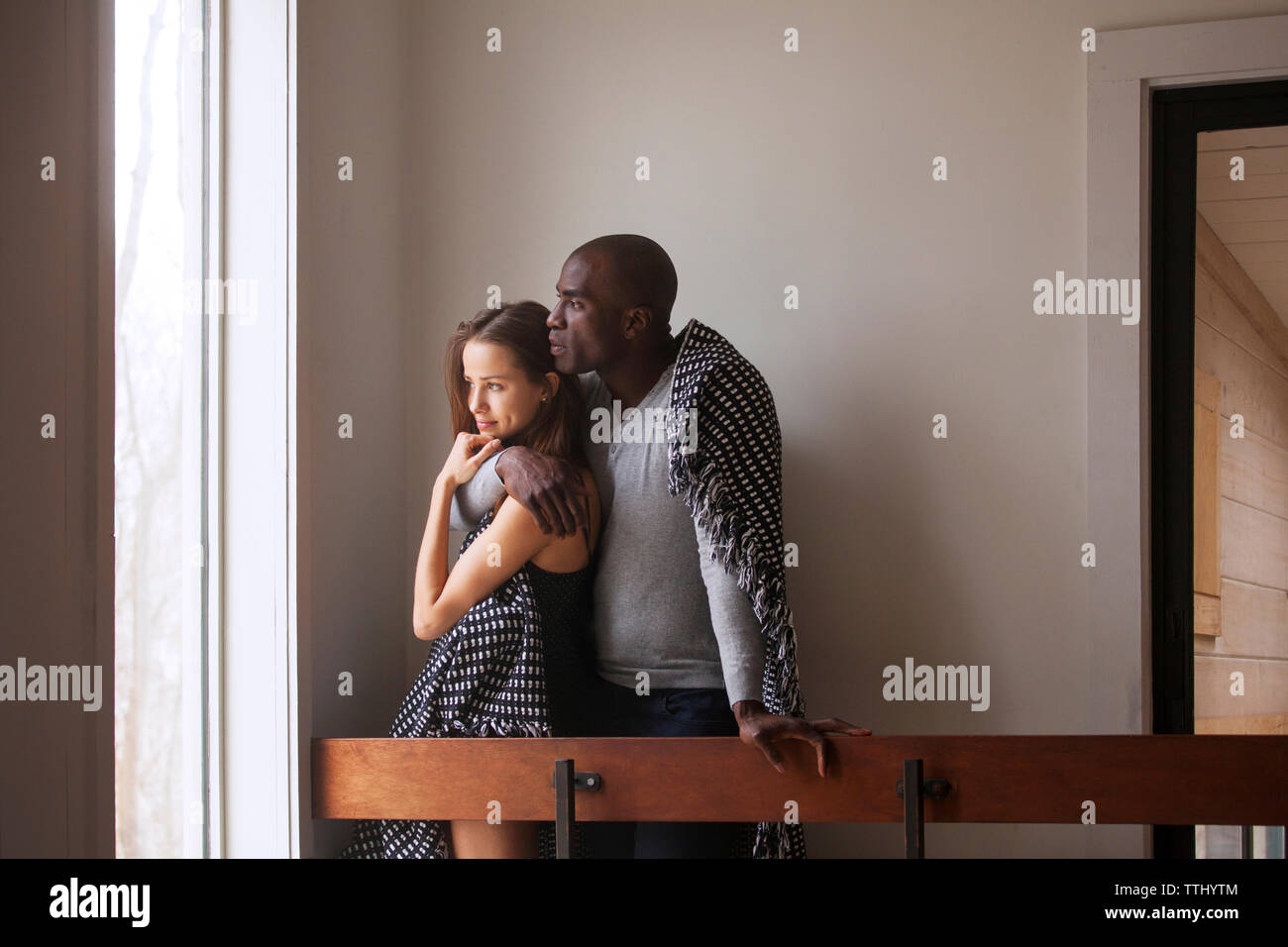 Couple looking away while standing by railing at home Stock Photo