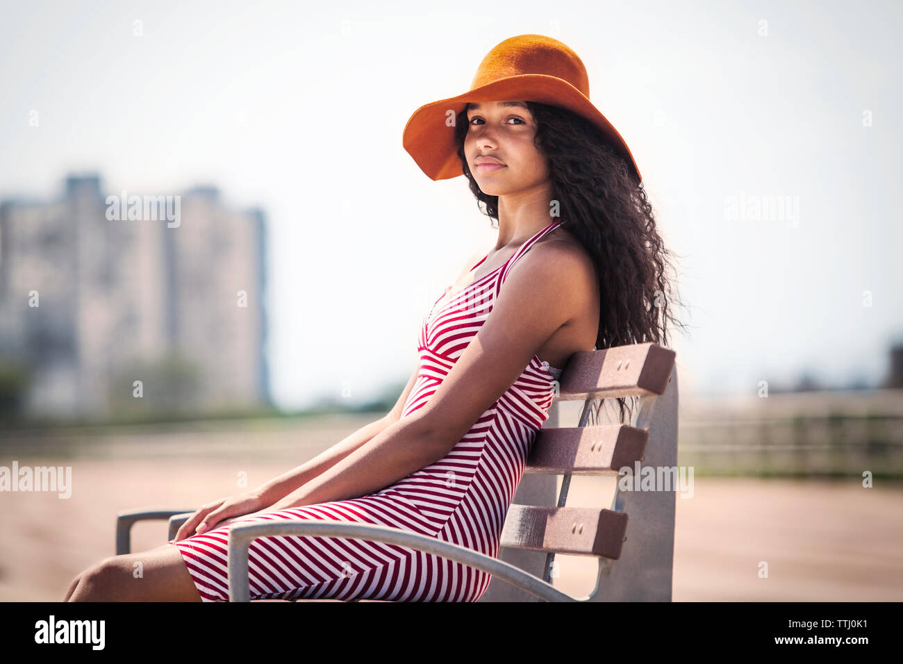 Portrait of girl sitting on bench at pier Stock Photo