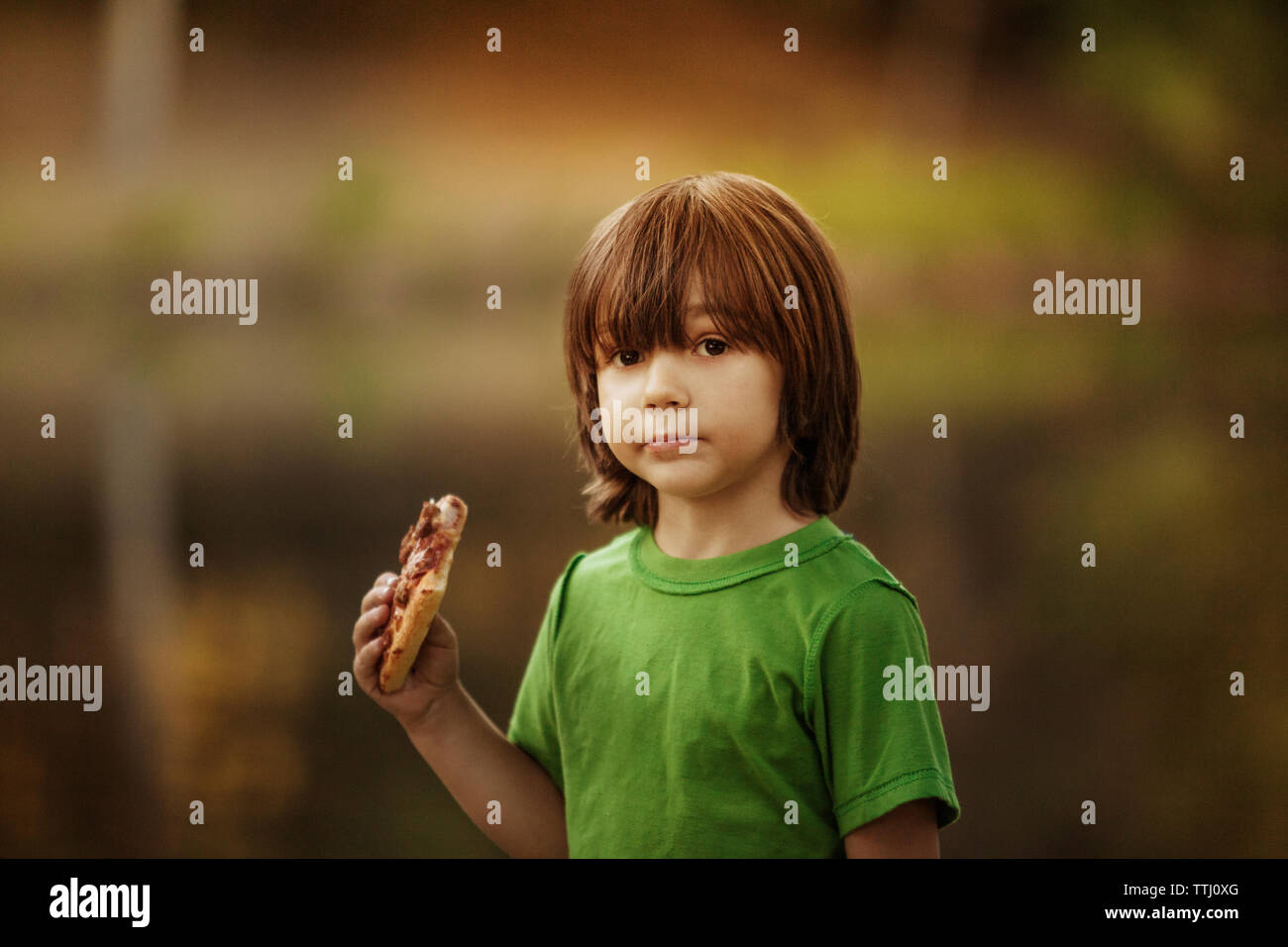 Portrait of boy holding pizza slice Stock Photo - Alamy
