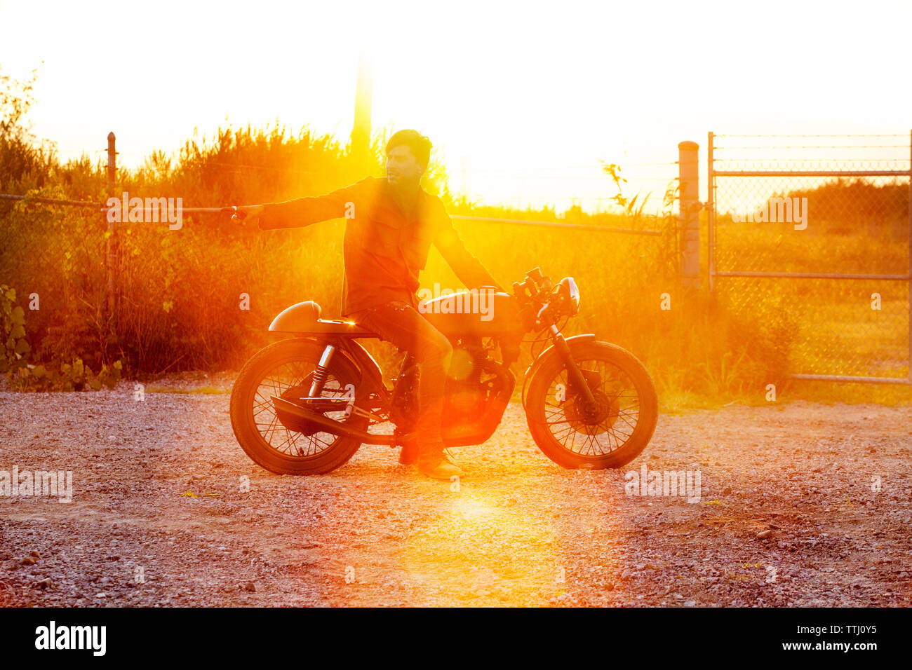 Man pointing while sitting on motorcycle against clear sky Stock Photo