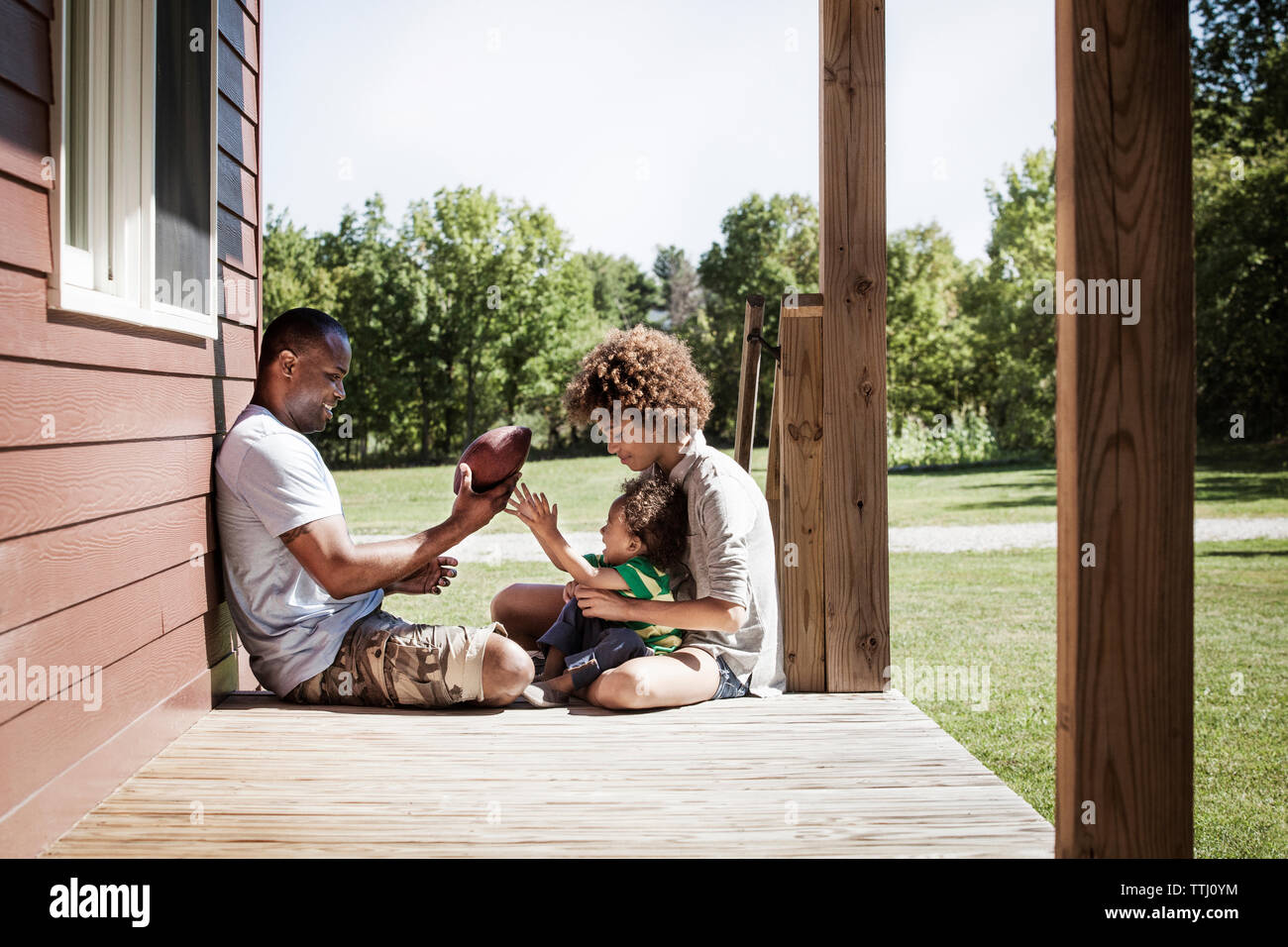 Father and children with football sitting on porch Stock Photo