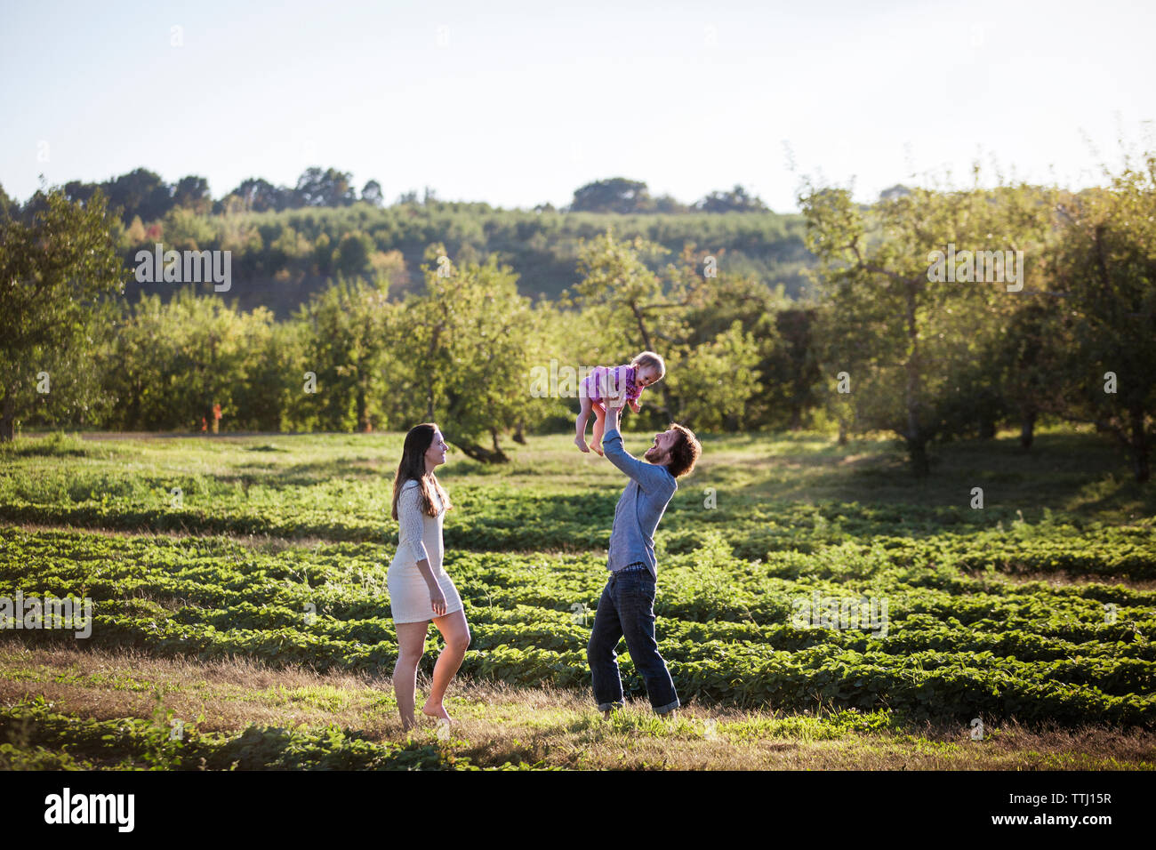 Man lifting daughter while standing with wife on field Stock Photo