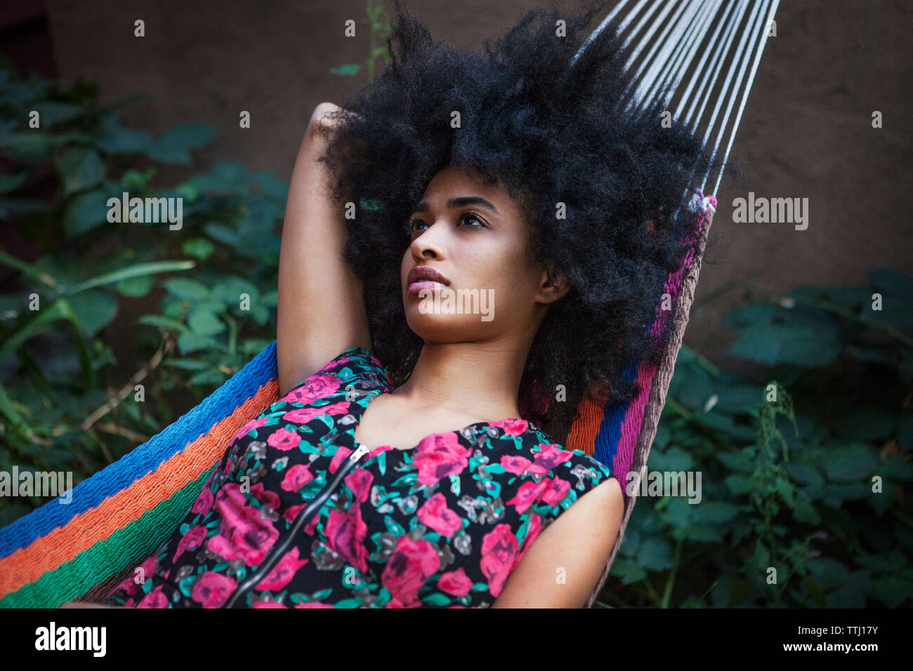 Woman with frizzy hair looking away while lying on hammock Stock Photo