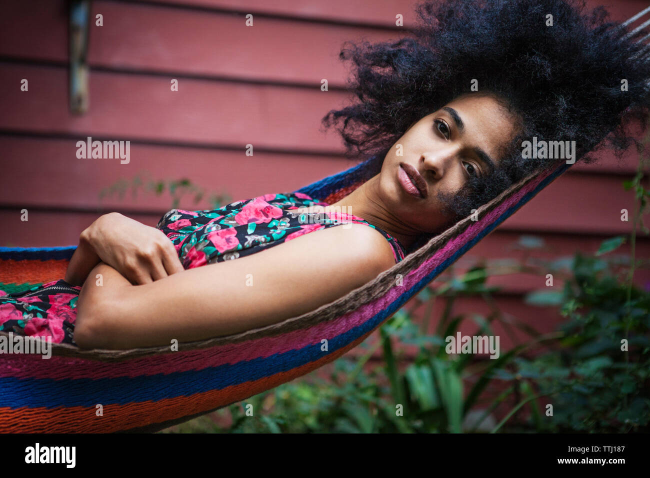 Woman with arms crossed relaxing on hammock in lawn Stock Photo