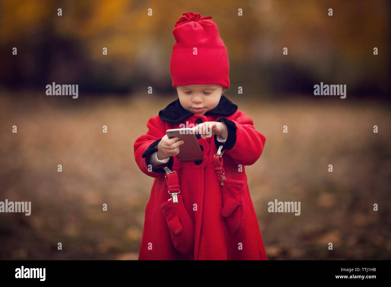 Cute baby girl using smart phone while standing on field Stock ...
