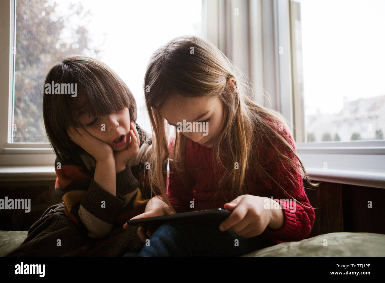 Boy looking at sister using tablet computer at home Stock Photo