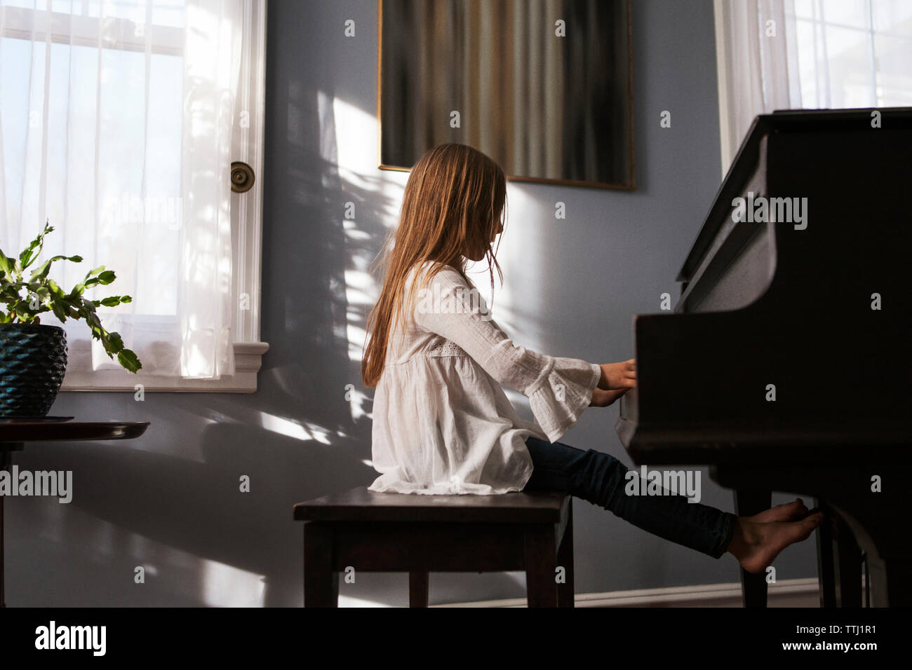 Side view of girl playing piano at home Stock Photo Alamy