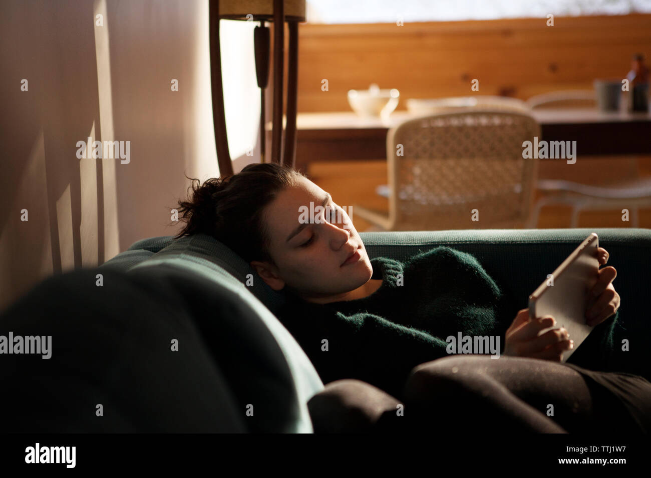 Teenage girl using tablet while sitting on sofa at home Stock Photo - Alamy