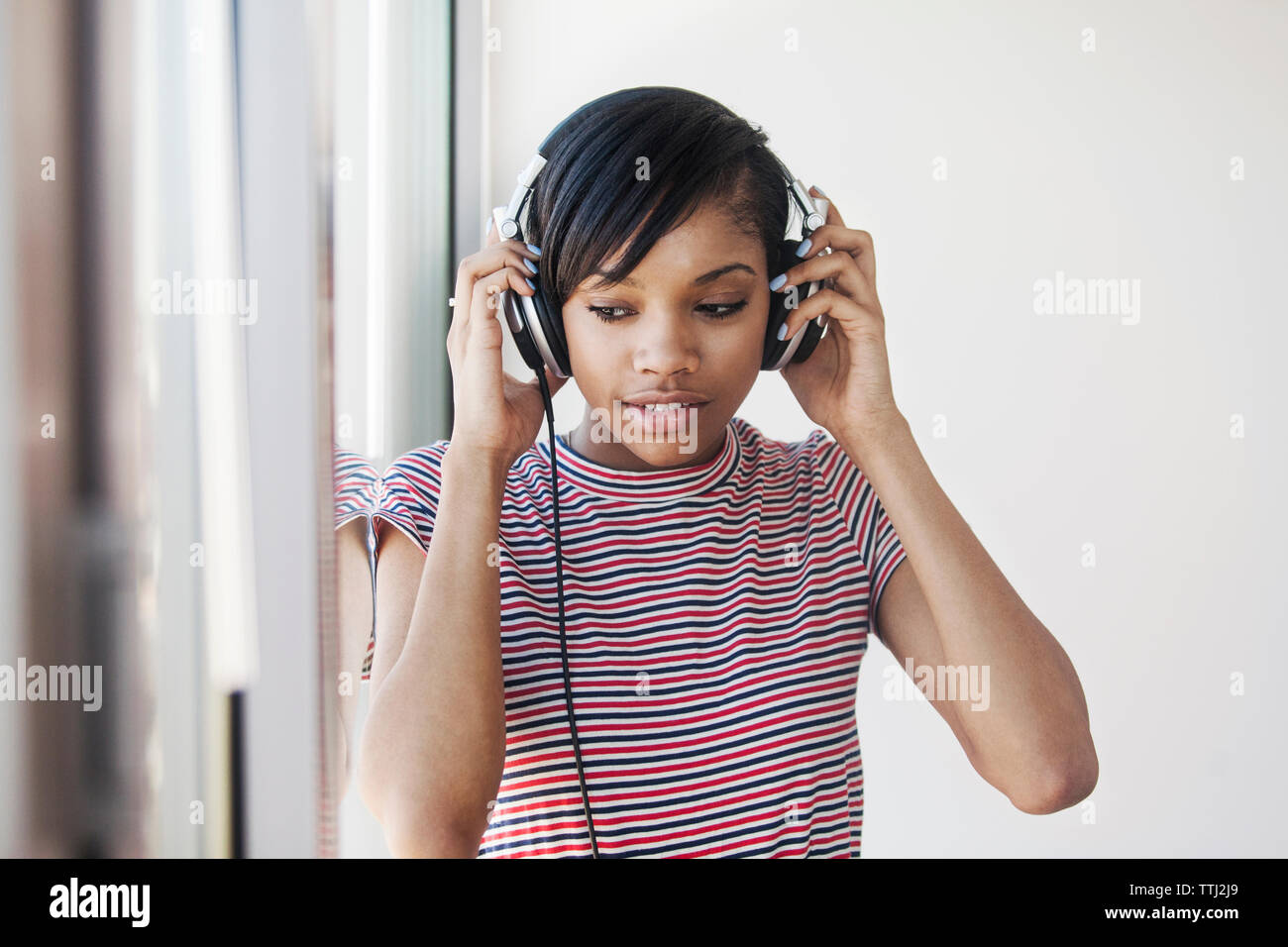 Woman looking away while wearing headphone at home Stock Photo
