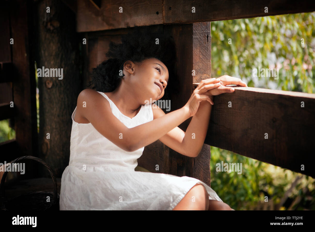 Smiling girl sitting in tree house Stock Photo