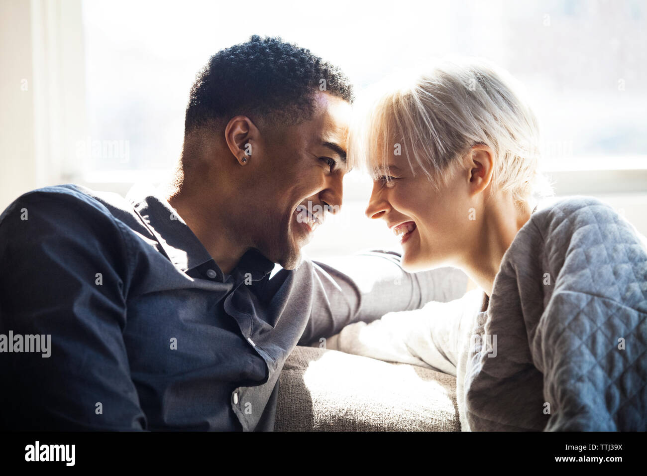 Happy couple looking at each other while sitting on sofa Stock Photo