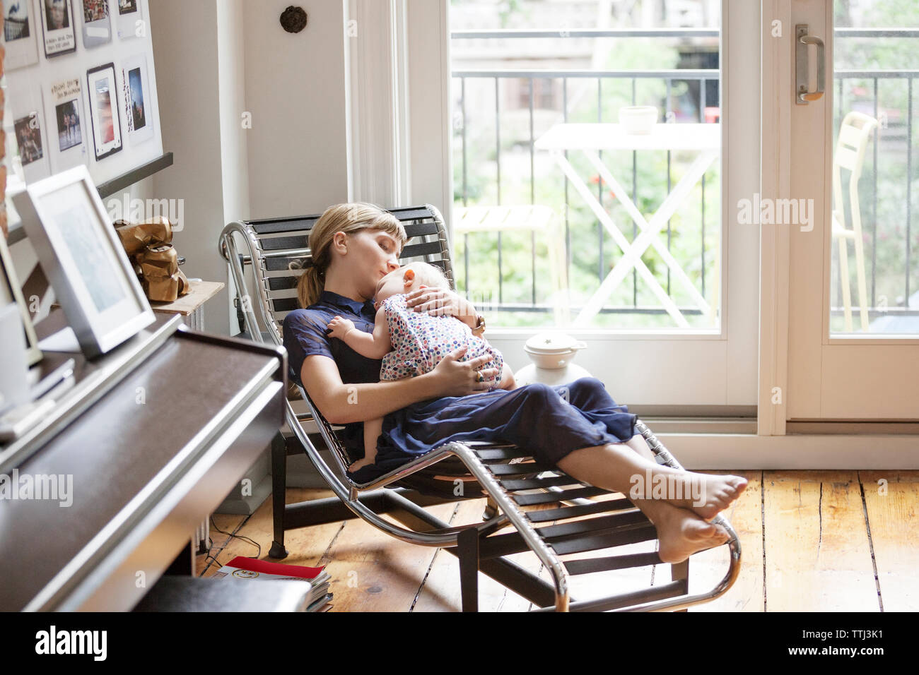 Mother and baby girl sleeping on lounge chair at home Stock Photo Alamy