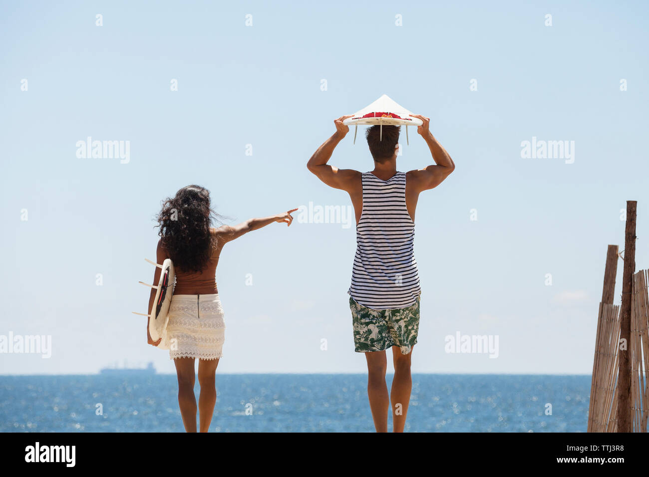 Woman pointing while standing with boyfriend at beach Stock Photo