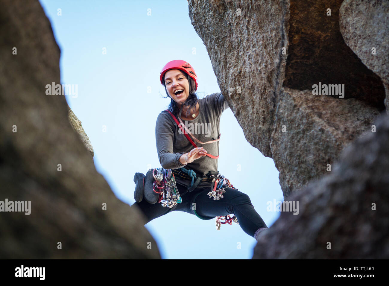 Low angle view of happy woman rock climbing Stock Photo