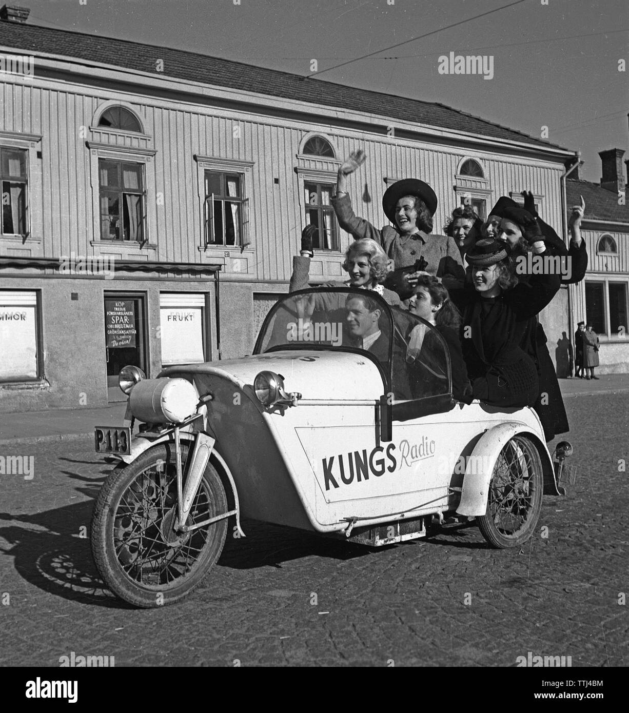 Driving in the 1940s. A man drives a three wheeled motorcycle and a group of women have joined the ride. Sweden 1943 Kristoffersson Ref A41-5 Stock Photo