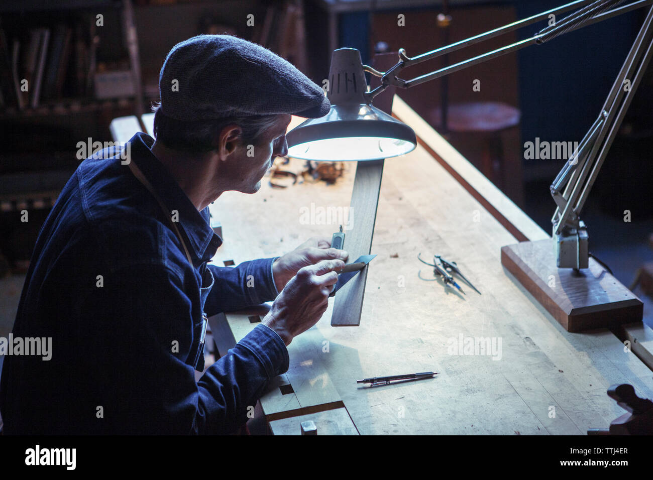 Carpenter using utility knife with wood at table in Stock