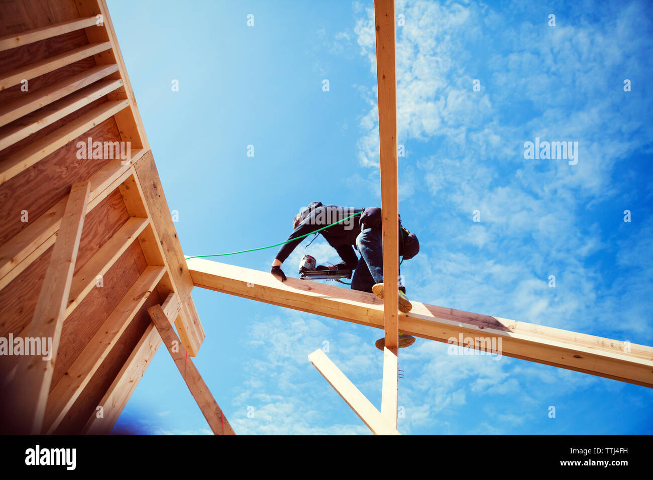 Low angle view of worker making construction frame against blue sky Stock Photo