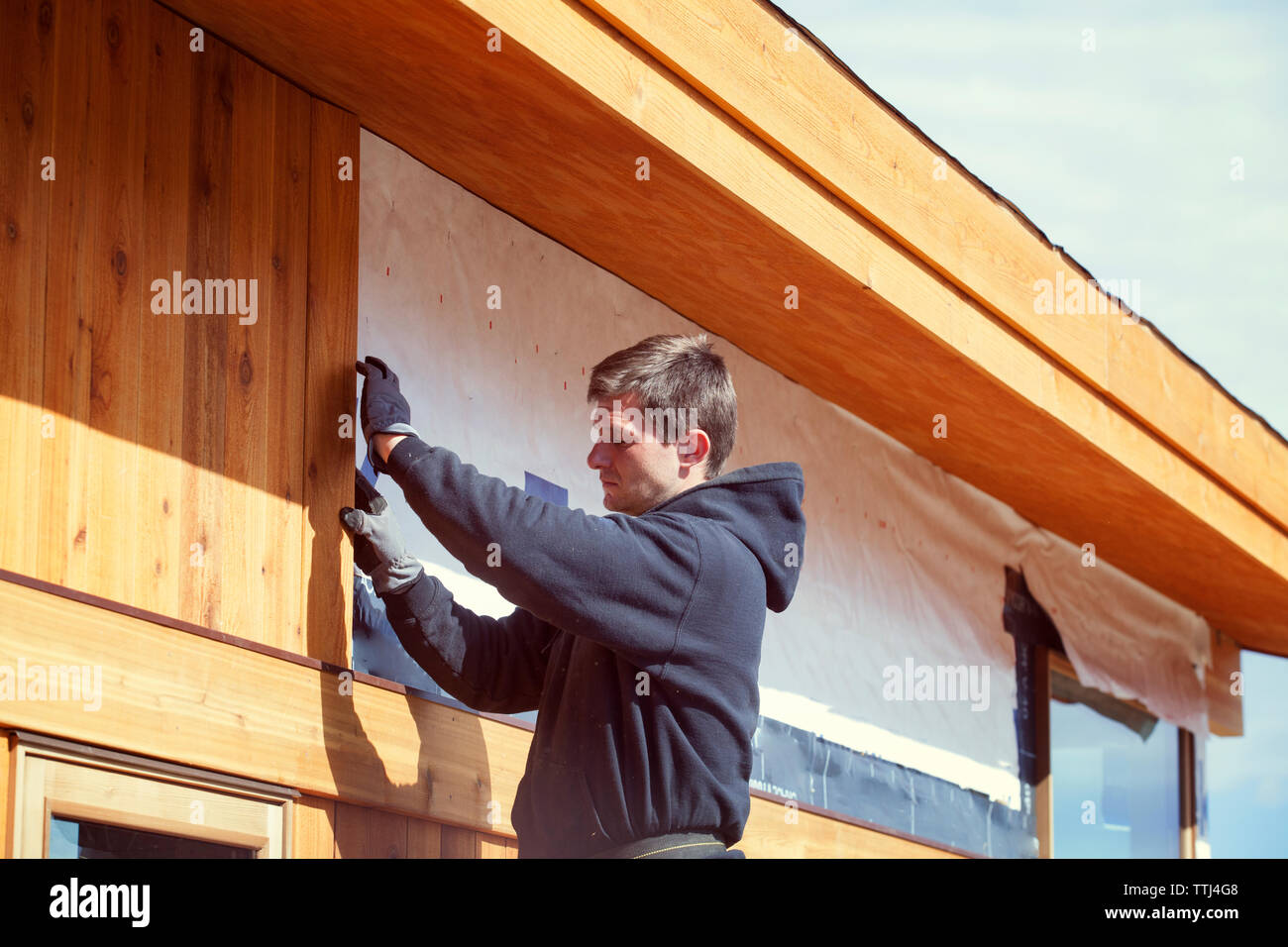 Worker constructing house during sunny day Stock Photo