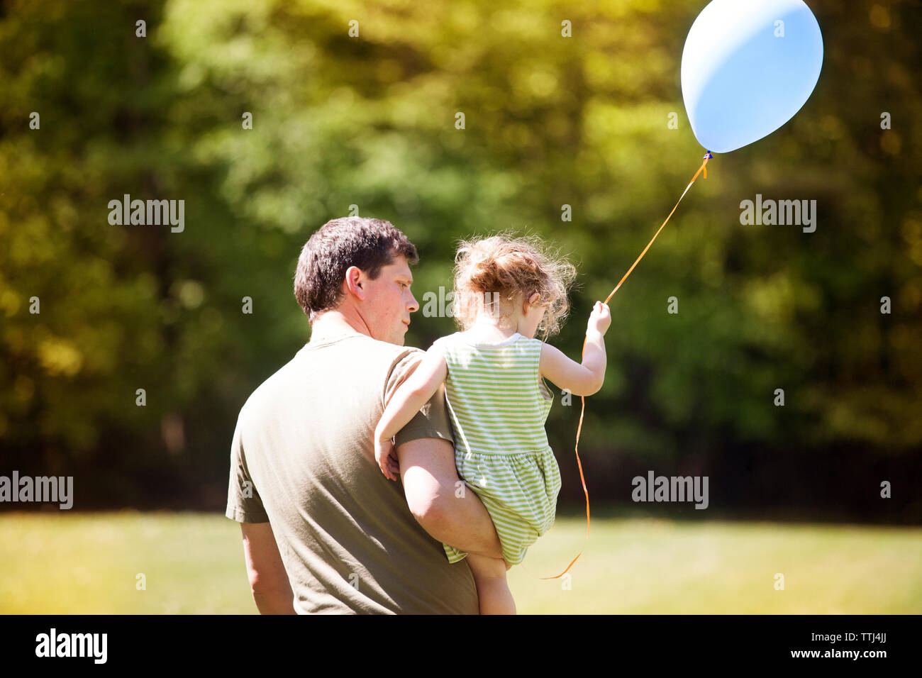 Rear view of father carrying daughter at park Stock Photo - Alamy