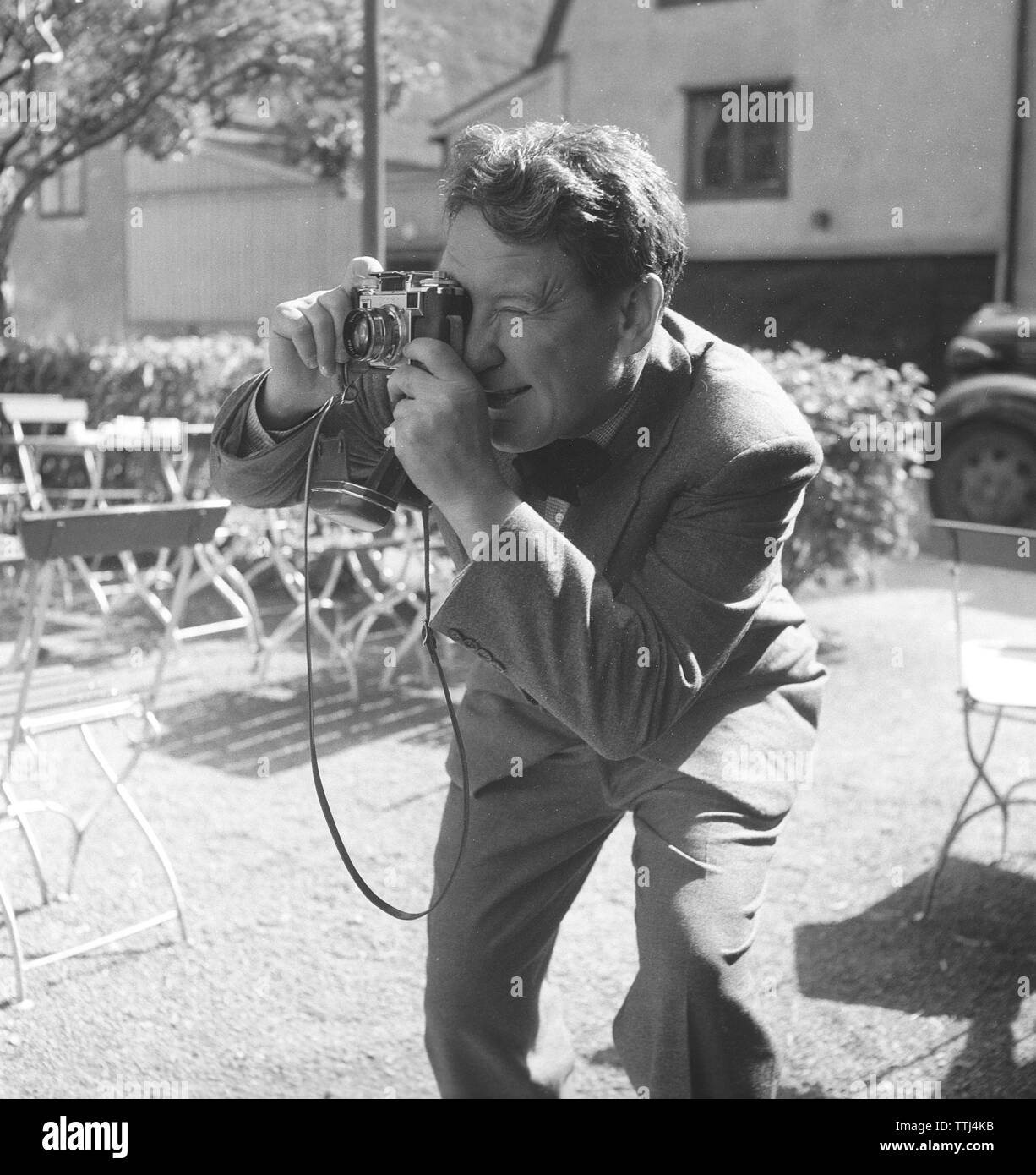 Amateur photographer in the 1950s. A young man is aiming to take a picture of something or someone with his camera. He is american actor Burgess Meredith taking a picture. Sweden 1954. Photo Kristoffersson Ref BF78-1 Stock Photo