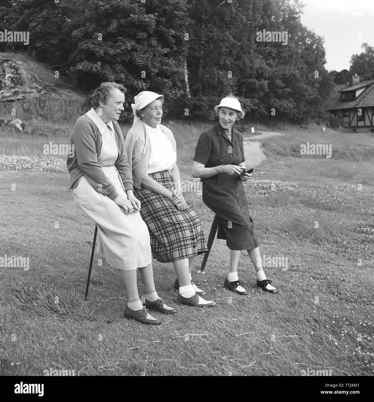 Back in the 1950s. Three elderly women rest their legs and are sitting on the practical one-legged resting chair they have brought along. Sweden 1955 Kristoffersson ref  BY15-10 Stock Photo