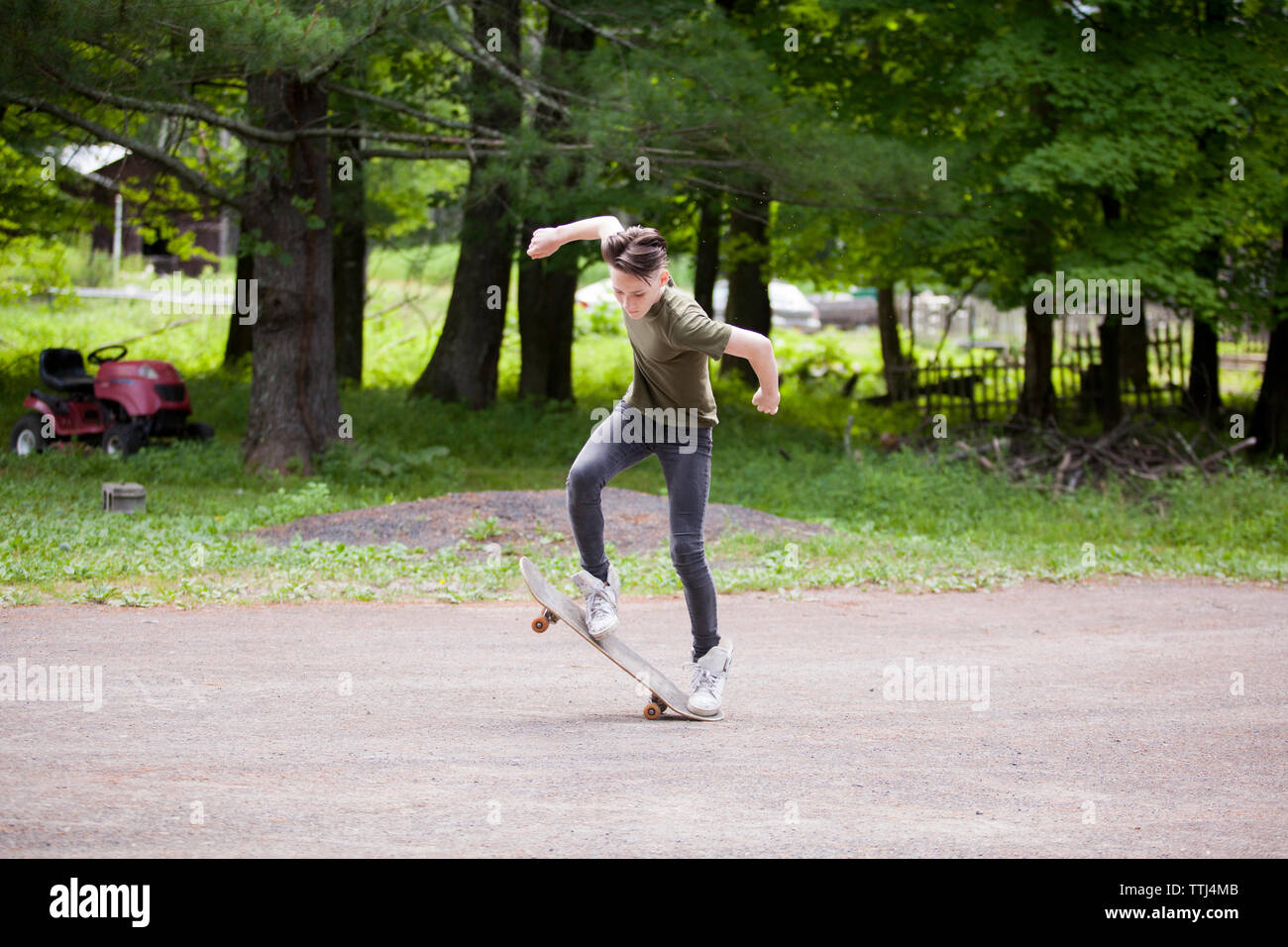 Full length of teenage boy skateboarding on road Stock Photo