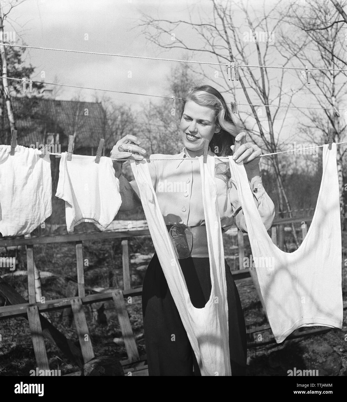 Doing the laundry in the 1940s. A lady is out in the garden hanging up the laundry to dry. Sweden 1947 Kristoffersson ref AB10-5. Sweden 1951 Stock Photo