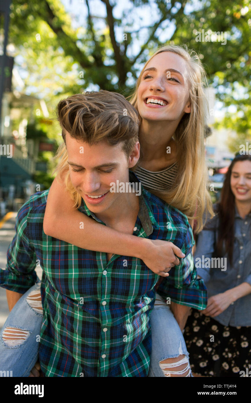 Man piggybacking woman by friend on street Stock Photo