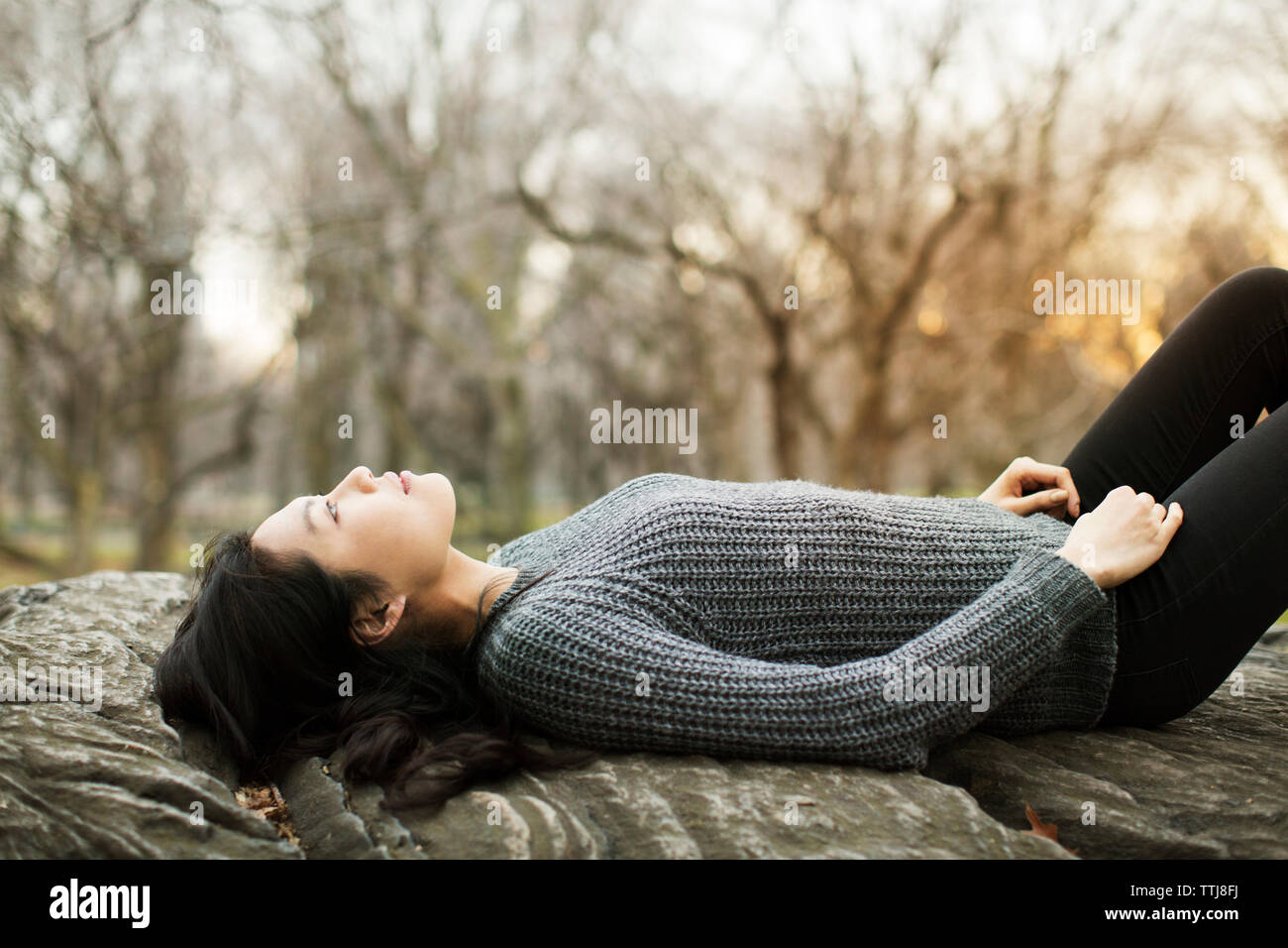 Thoughtful woman relaxing on rock Stock Photo