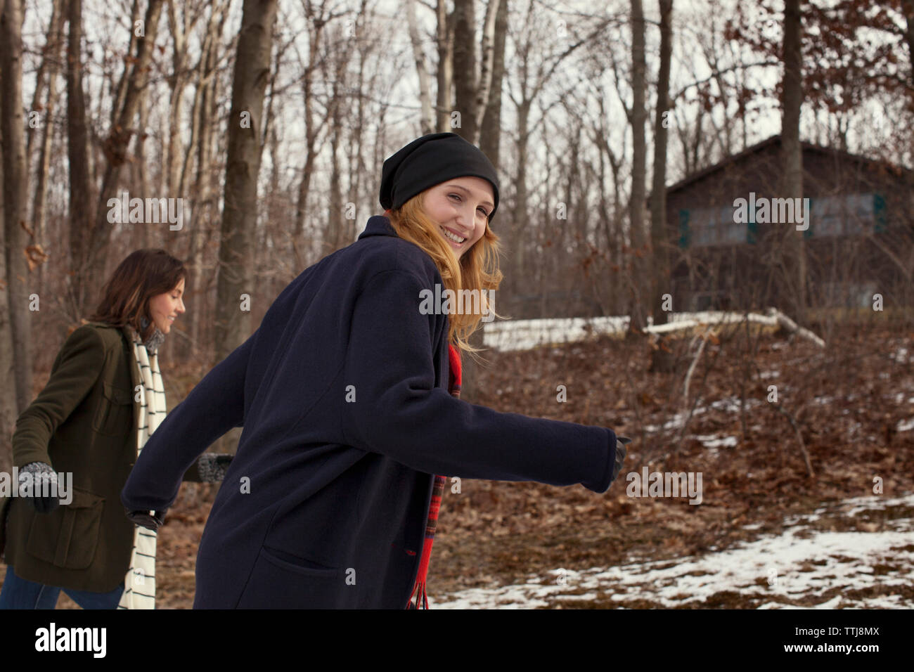 Portrait of woman walking with friend in forest during winter Stock Photo