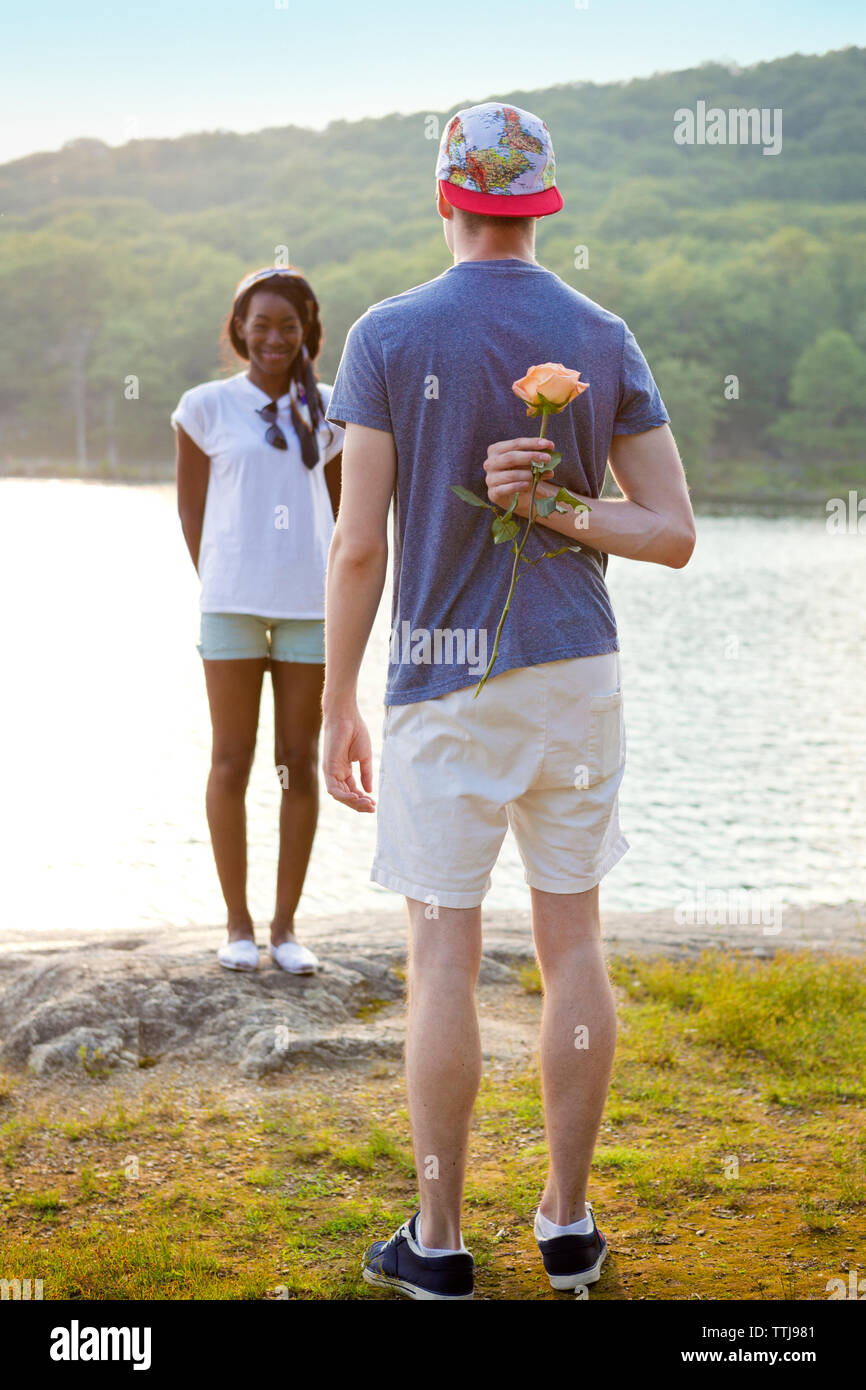 Rear view of man hiding rose behind back to propose girlfriend Stock Photo