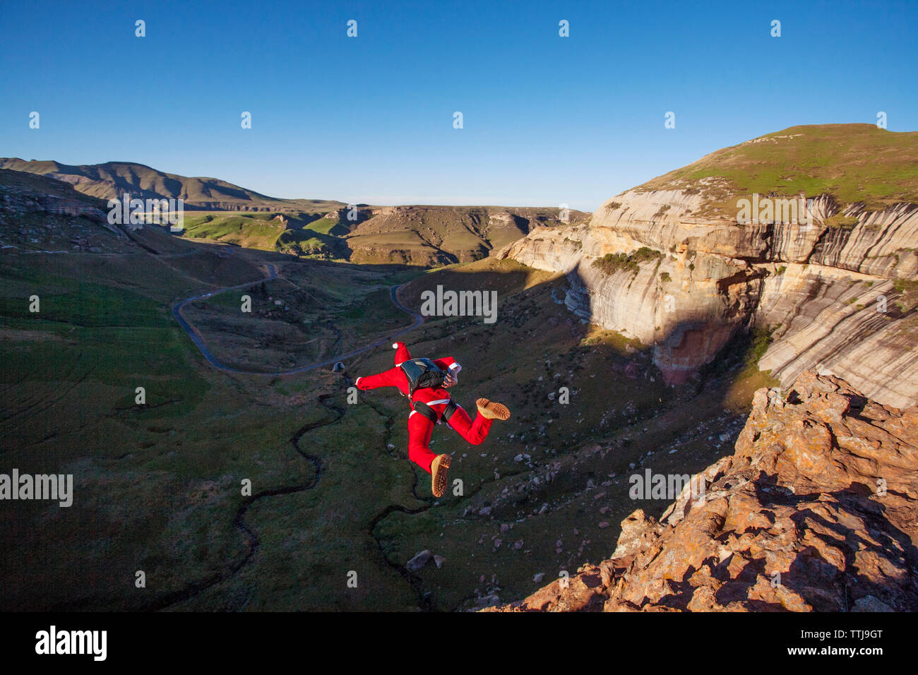 Rear view of man with parachute BASE jumping from cliff Stock Photo Alamy