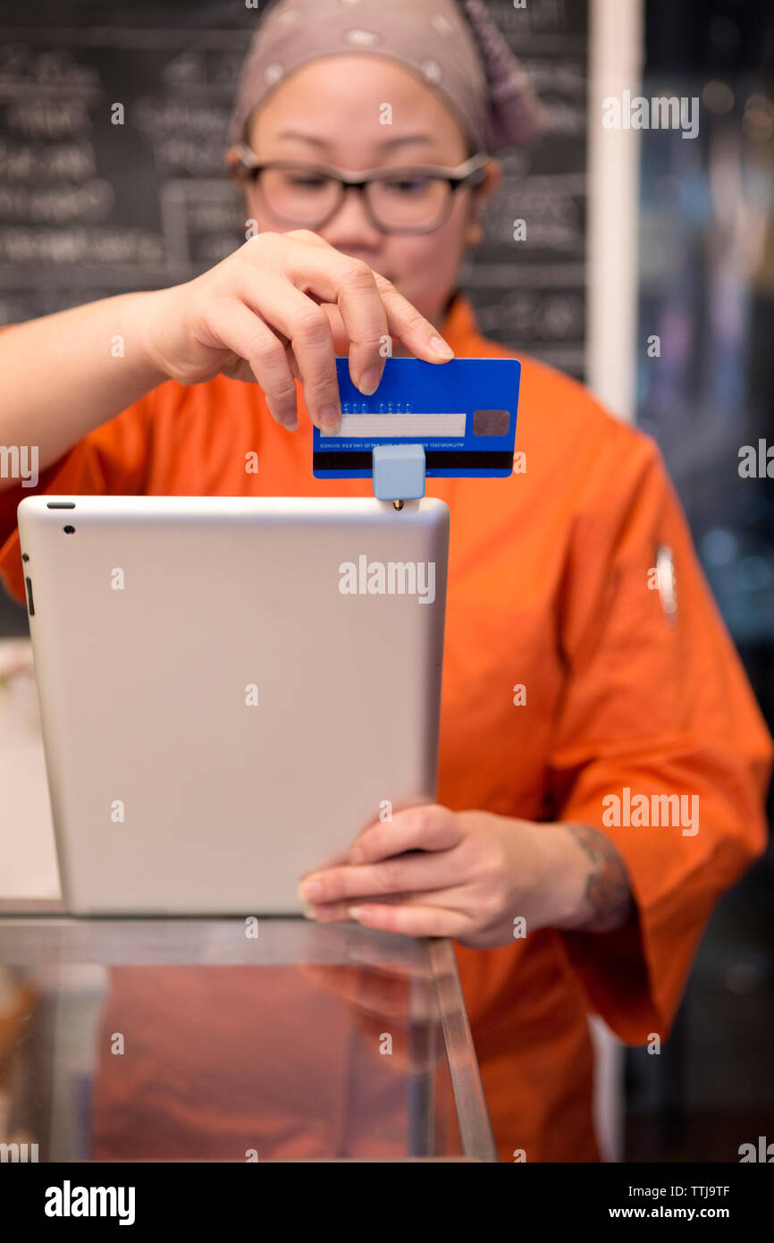 Female owner swiping credit card at store Stock Photo