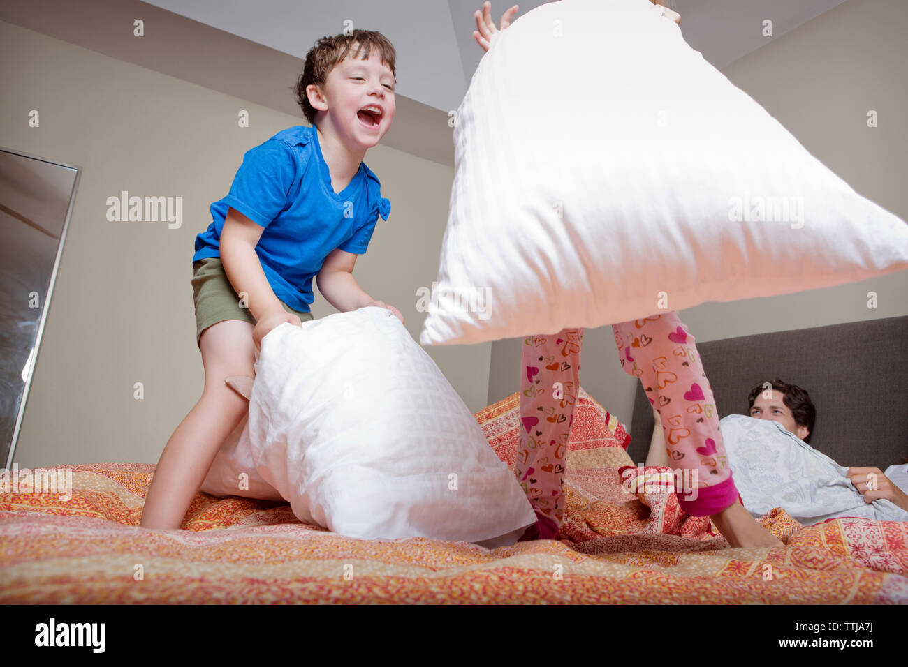 Kids playing pillow fight with parents on bed at home Stock Photo - Alamy, image size:1300x956