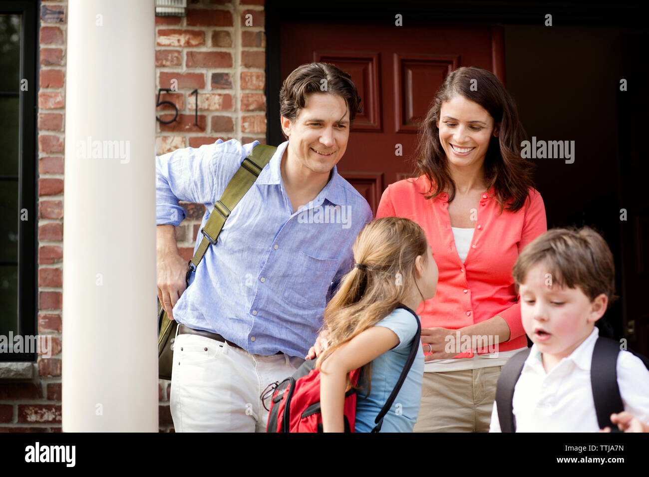Happy family standing against front door Stock Photo - Alamy