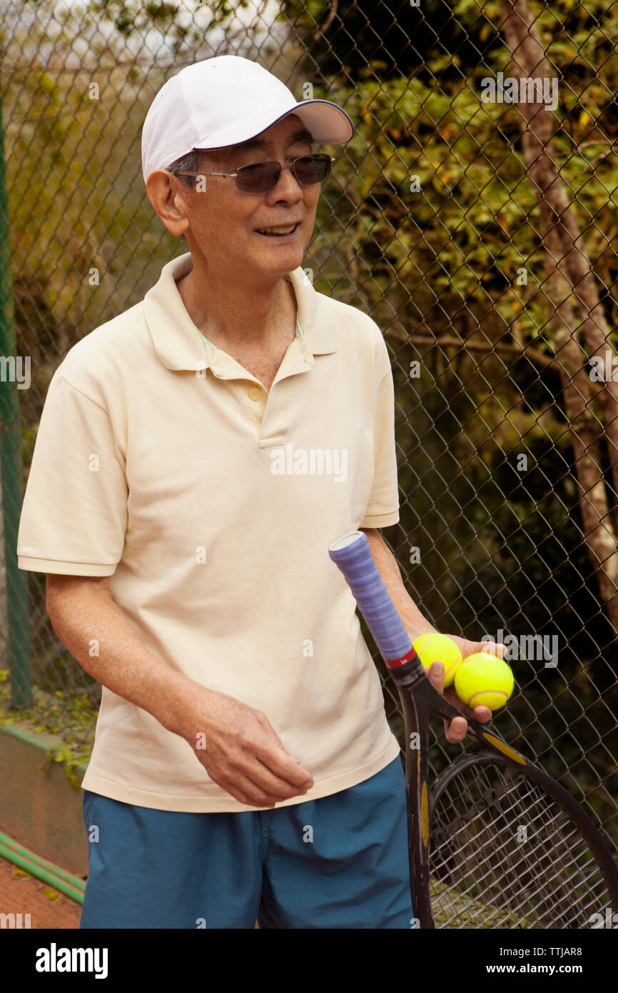 Man holding tennis racket and while standing at court Stock Photo