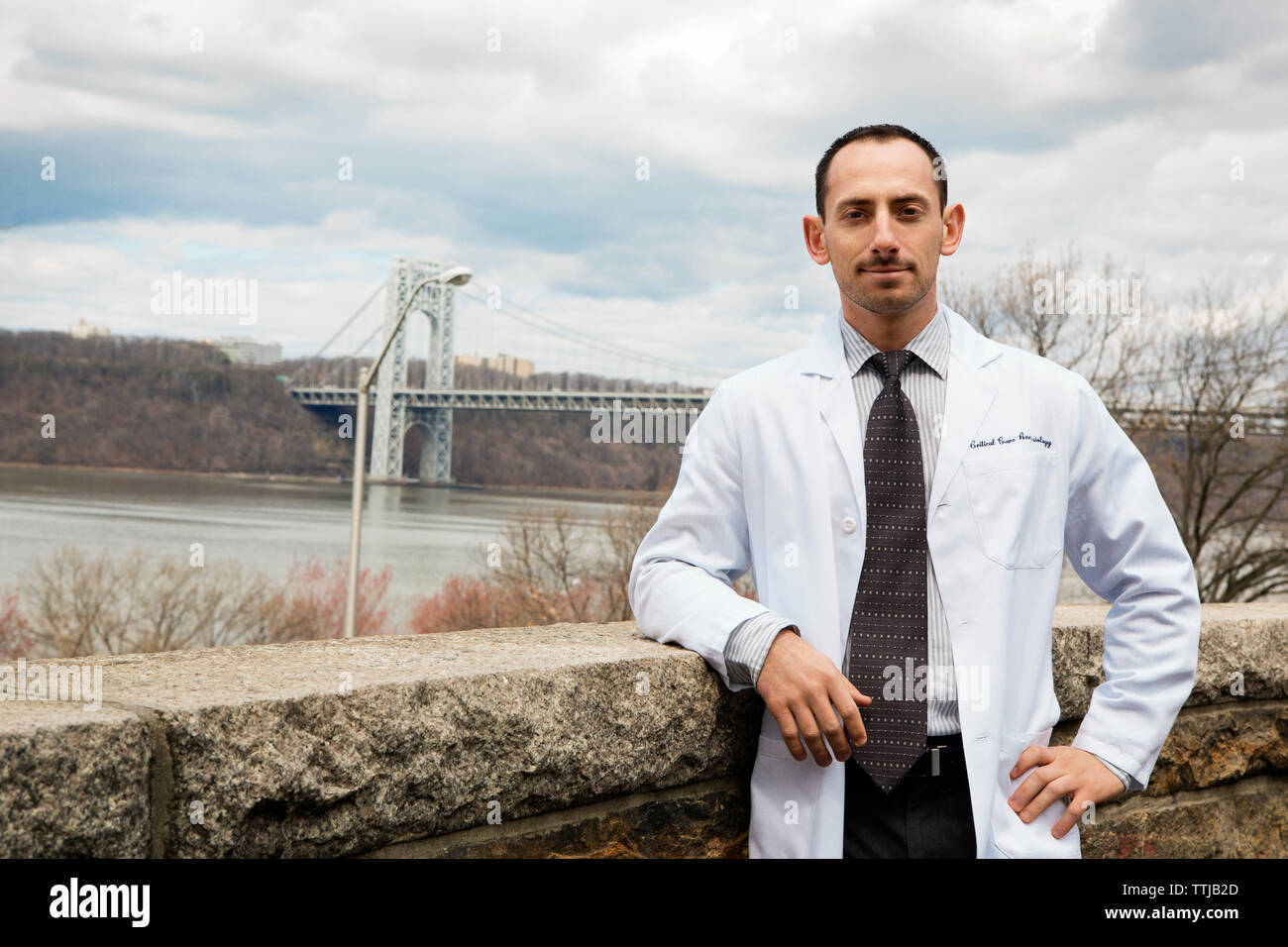 Portrait of doctor standing by retaining wall against bridge Stock Photo