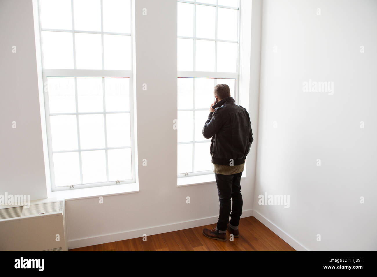 Man using mobile phone while sitting with son at window in home Stock Photo