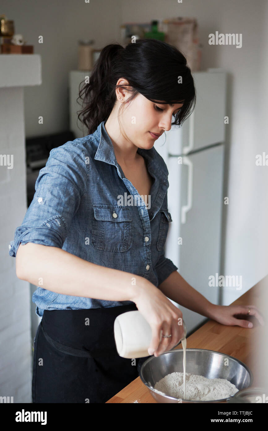 Woman pouring milk in bowl Stock Photo