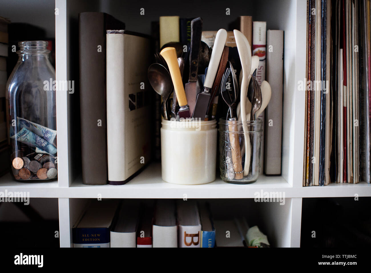 Cutleries in containers on bookshelves Stock Photo