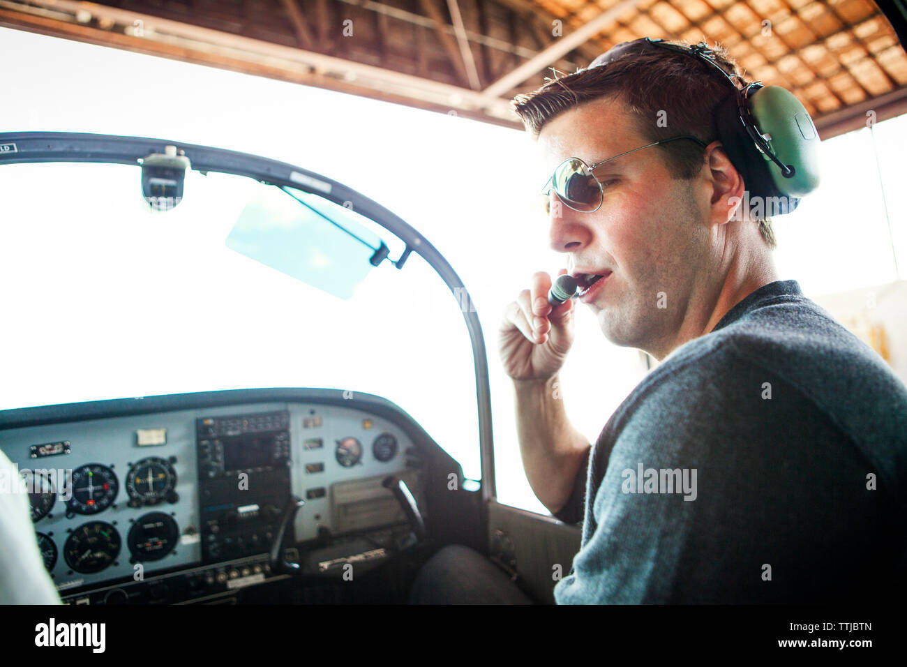 Mechanic examining headphones while sitting in airplane Stock Photo