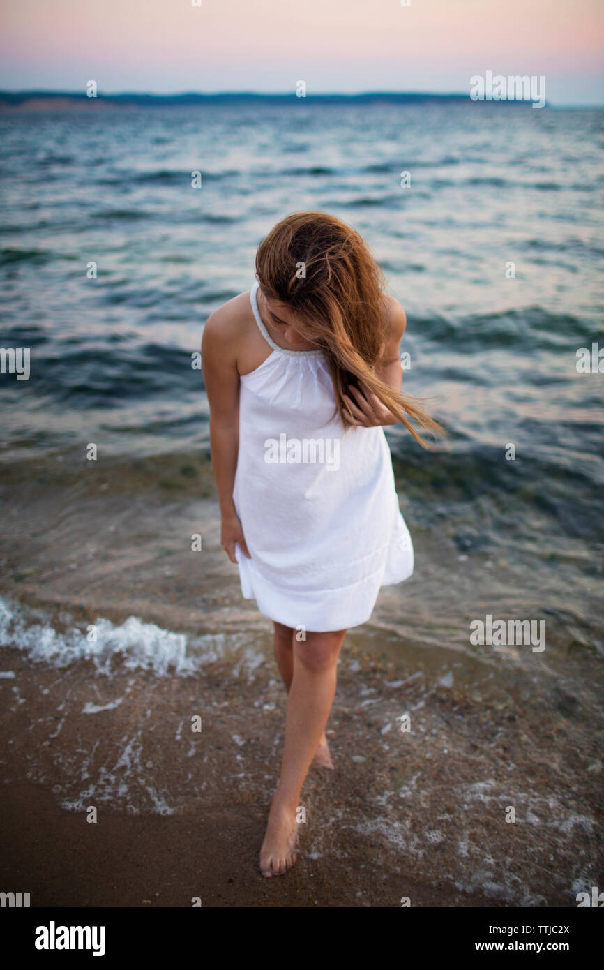 Woman looking down while standing on shore at beach Stock Photo