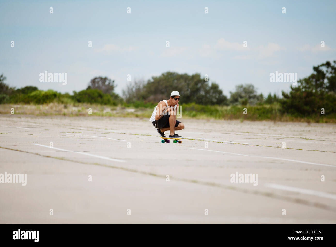 Man performing stunt on skateboard at field against sky Stock Photo