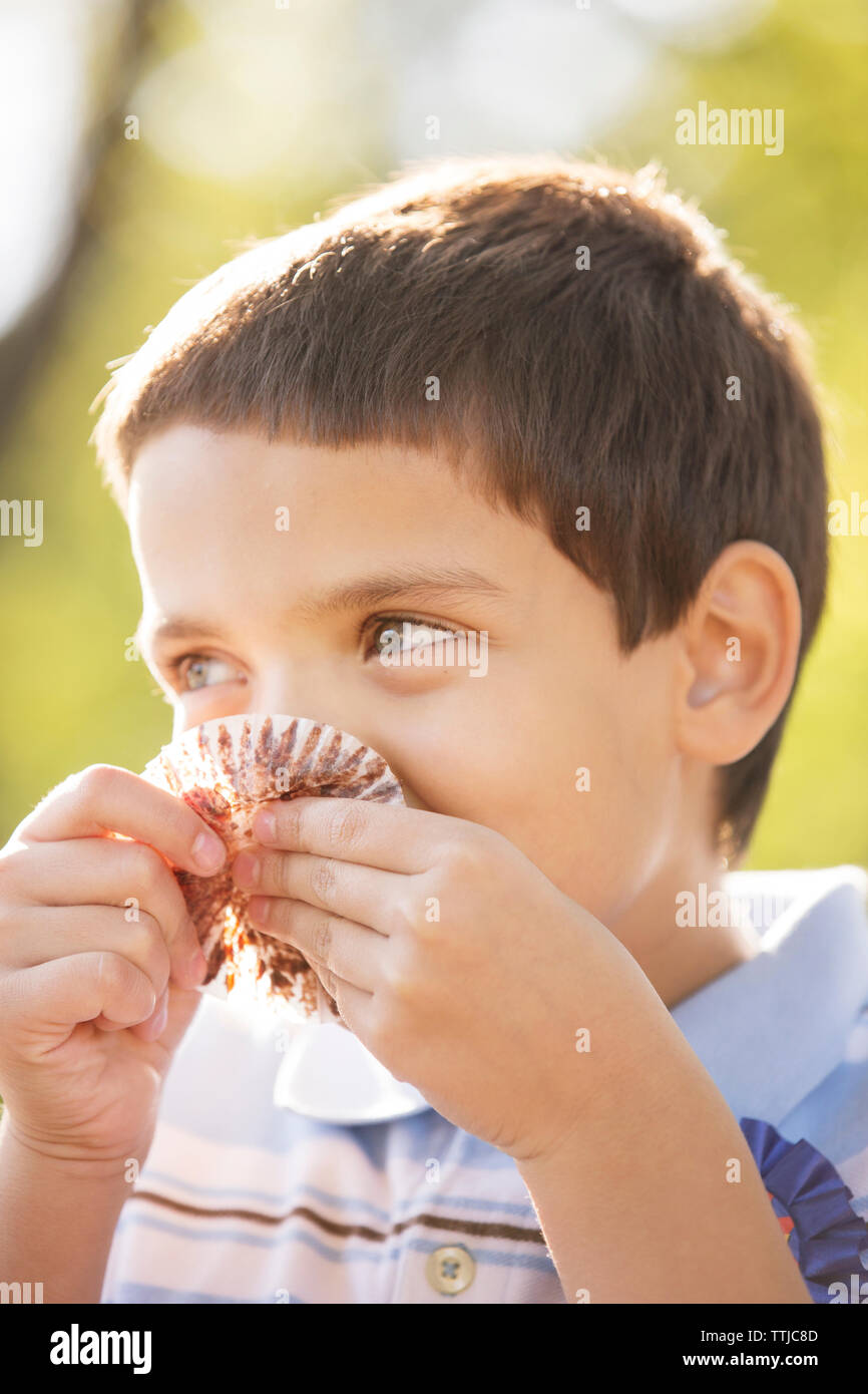 Boy looking away while eating cupcake at party Stock Photo