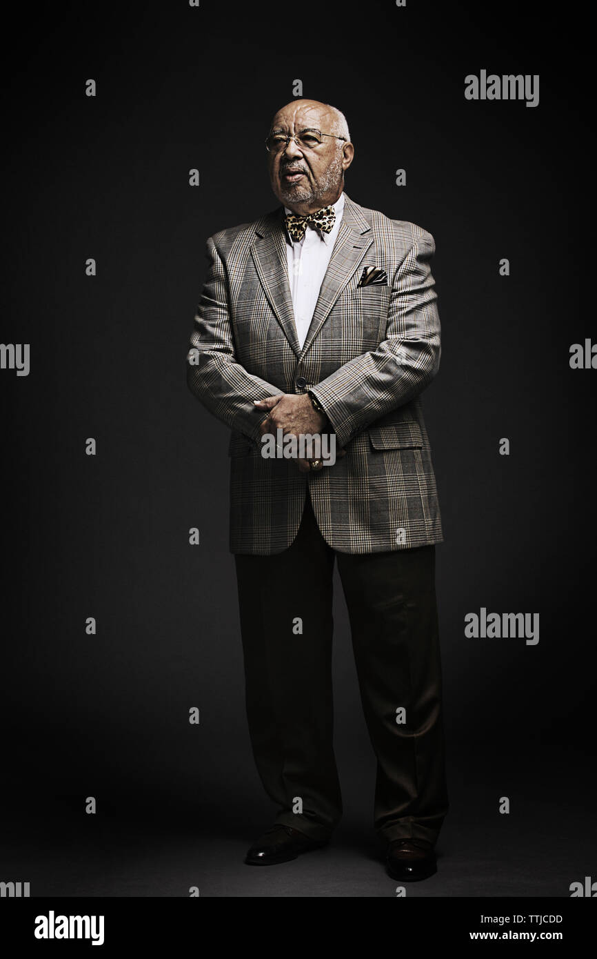 Senior man looking away while standing against black background Stock Photo