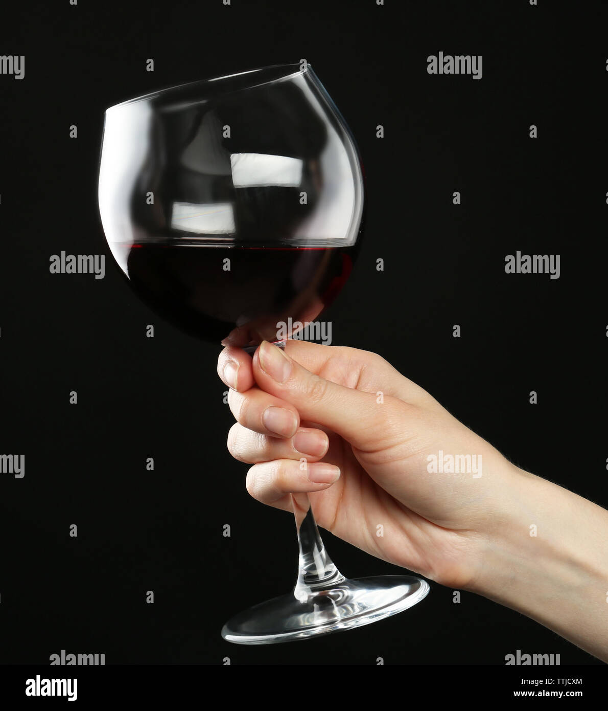 Female hand holding glass of red wine on black background Stock Photo ...